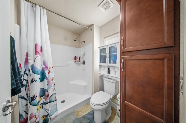 bathroom featuring visible vents, a shower stall, a textured ceiling, and toilet