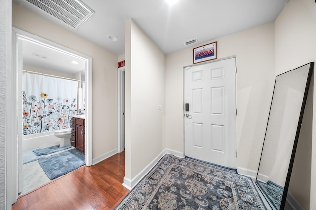 entryway with wood finished floors, visible vents, and baseboards
