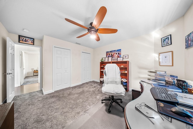 home office with visible vents, carpet flooring, baseboards, and a ceiling fan