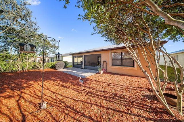 rear view of property with metal roof, a sunroom, and a patio area