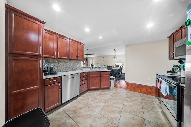 kitchen featuring light stone counters, light tile patterned floors, a peninsula, stainless steel appliances, and tasteful backsplash