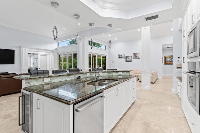 kitchen featuring beverage cooler, decorative columns, a sink, appliances with stainless steel finishes, and open floor plan
