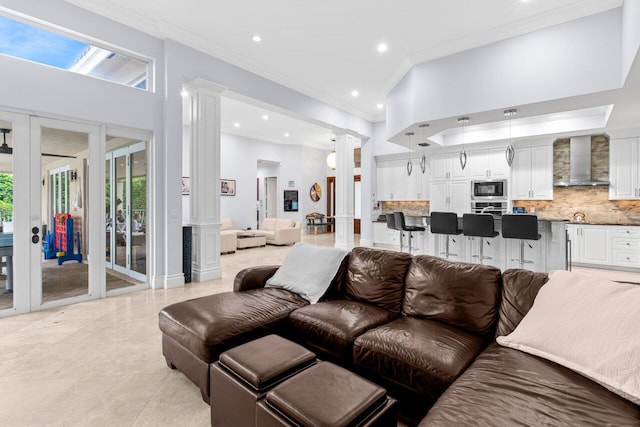 living area with a towering ceiling, recessed lighting, ornate columns, and ornamental molding