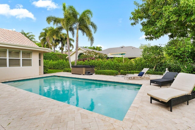 outdoor pool featuring a patio area and a hot tub