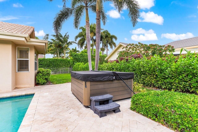 view of patio / terrace featuring a swimming pool, fence, and a hot tub
