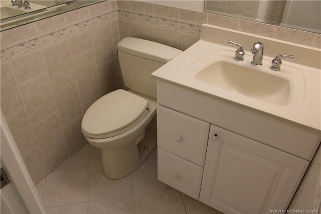 half bathroom with tile patterned floors, toilet, tile walls, and vanity
