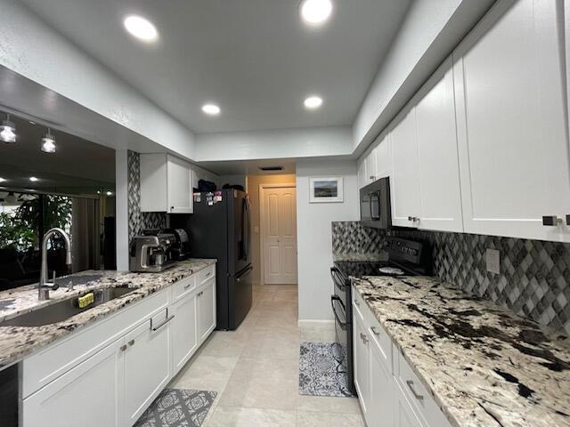 kitchen with black appliances, tasteful backsplash, and a sink