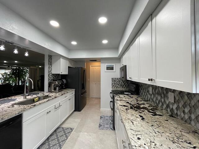 kitchen featuring black appliances, backsplash, white cabinetry, and a sink