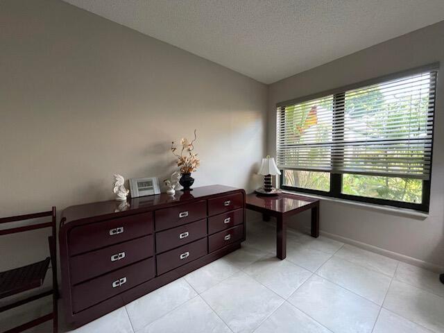 office area with lofted ceiling, a textured ceiling, baseboards, and light tile patterned floors
