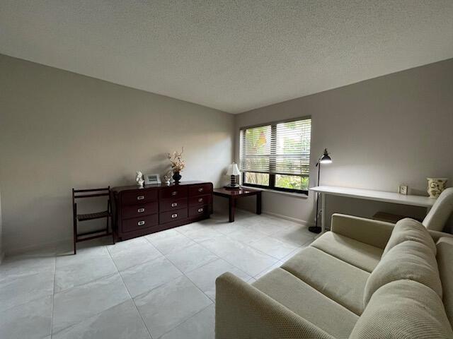 living area featuring light tile patterned flooring, a textured ceiling, and baseboards