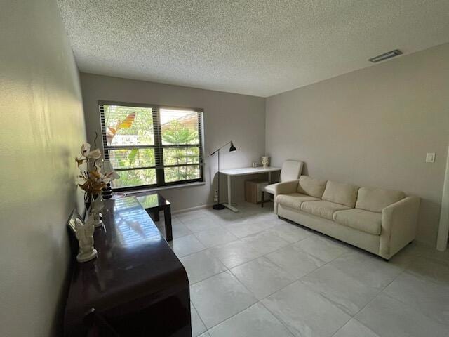 living room featuring light tile patterned flooring, a textured ceiling, and visible vents