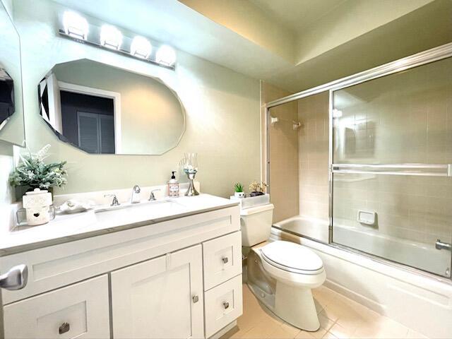 bathroom featuring toilet, vanity, tile patterned floors, and shower / bath combination with glass door