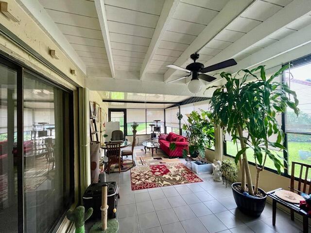 sunroom / solarium with beamed ceiling, tile patterned floors, ceiling fan, and outdoor lounge area