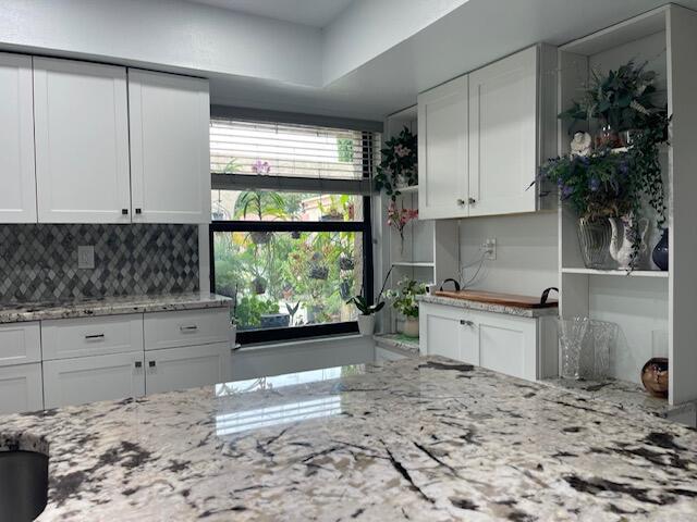 kitchen with white cabinets, decorative backsplash, and light stone countertops