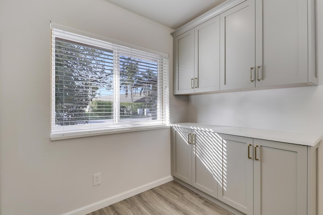 interior space featuring light countertops, baseboards, gray cabinets, and light wood-type flooring