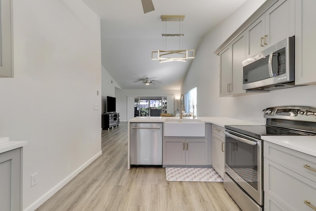 kitchen with a ceiling fan, light wood-style floors, appliances with stainless steel finishes, a peninsula, and light countertops