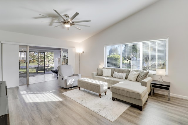 living area with baseboards, lofted ceiling, wood finished floors, and a ceiling fan