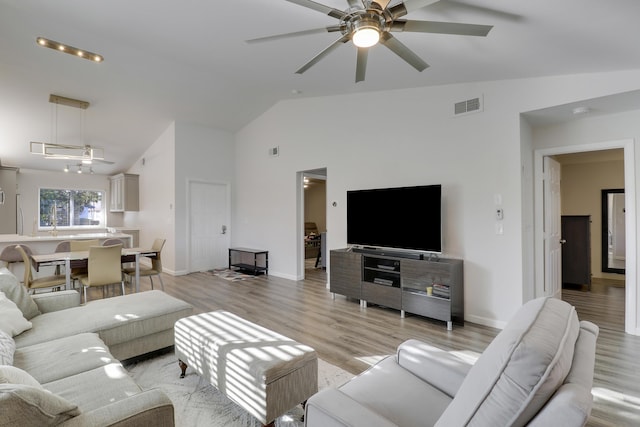 living area featuring a ceiling fan, visible vents, baseboards, high vaulted ceiling, and light wood-style floors