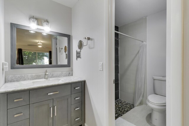 bathroom with a stall shower, toilet, vanity, and ceiling fan