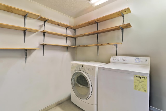 clothes washing area with laundry area, washing machine and dryer, and a textured ceiling