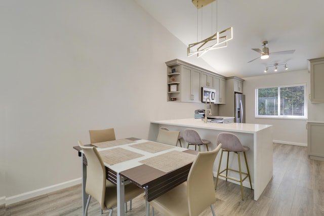 dining room with light wood-type flooring, lofted ceiling, baseboards, and a ceiling fan