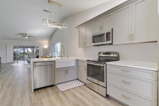 kitchen featuring gray cabinets, appliances with stainless steel finishes, a peninsula, and a sink