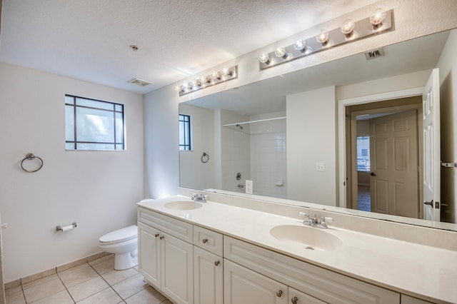 bathroom with a shower, toilet, tile patterned flooring, double vanity, and baseboards