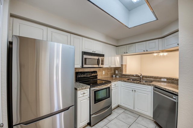 kitchen with stainless steel appliances, a sink, white cabinetry, and light tile patterned floors