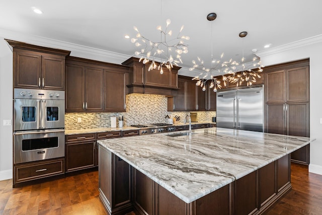 kitchen with a sink, dark wood-style floors, a chandelier, and stainless steel appliances