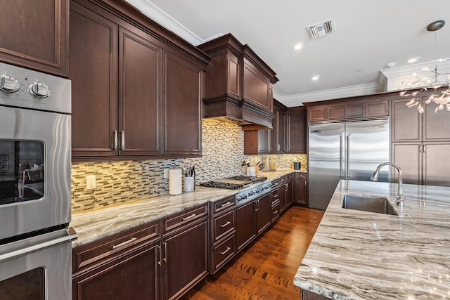 kitchen with a sink, stainless steel appliances, light stone countertops, and visible vents