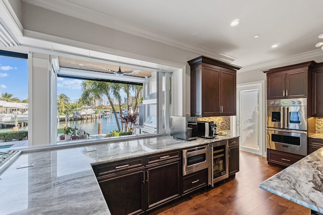 kitchen featuring beverage cooler, double oven, crown molding, decorative backsplash, and light stone countertops
