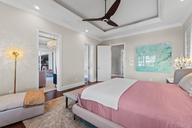 bedroom featuring baseboards, crown molding, a tray ceiling, and wood finished floors