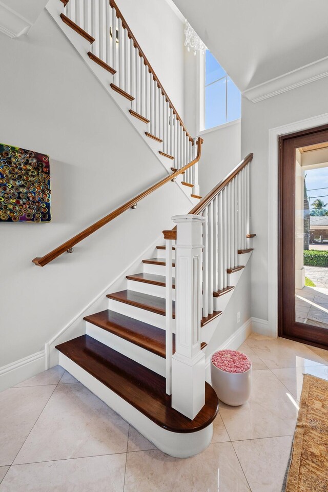 staircase featuring baseboards, ornamental molding, and tile patterned flooring