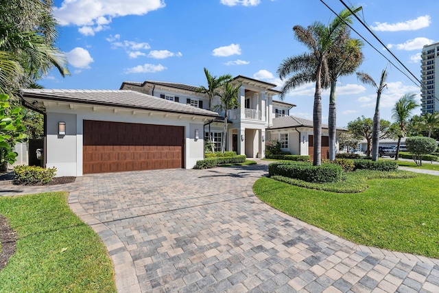 view of front of property featuring a balcony, decorative driveway, a garage, and stucco siding