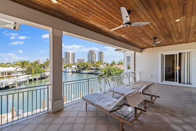 view of patio / terrace with a city view, a balcony, ceiling fan, and a water view