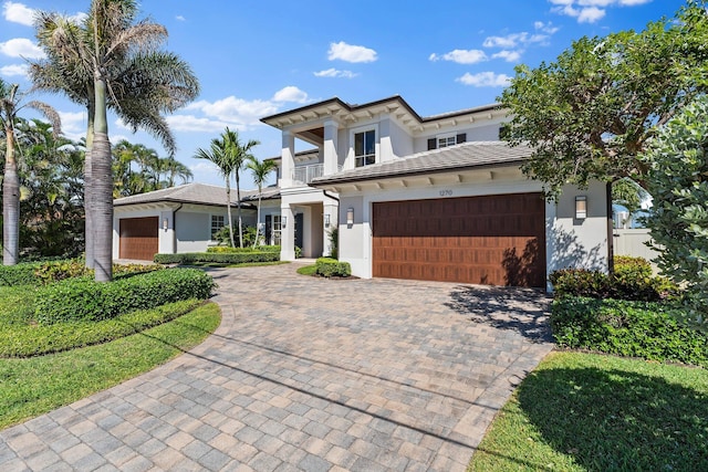 view of front of property featuring stucco siding, a tile roof, decorative driveway, and a balcony
