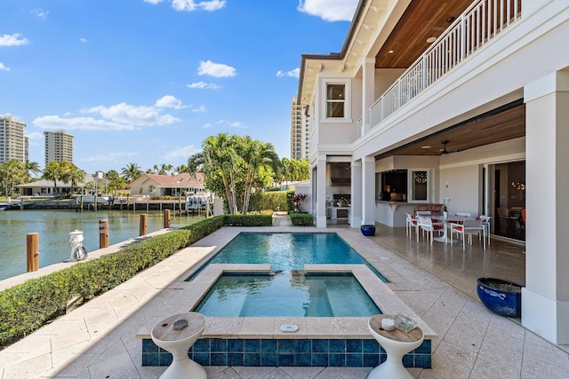 view of swimming pool with a water view, a pool with connected hot tub, and a patio area