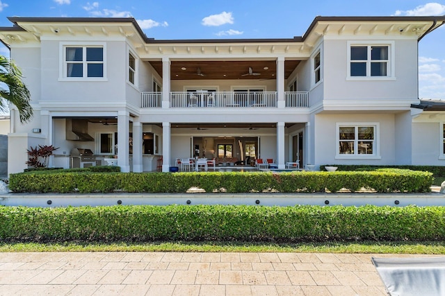 rear view of house featuring a balcony, a ceiling fan, and stucco siding
