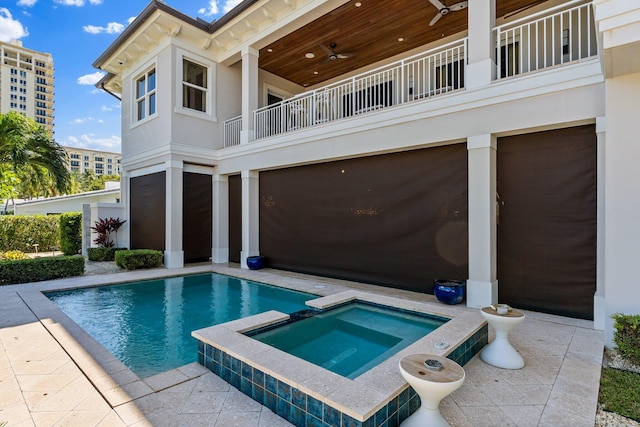 view of pool with a ceiling fan and a pool with connected hot tub