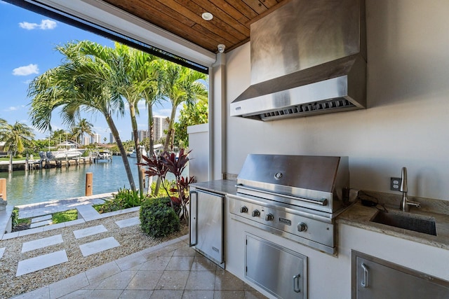 view of patio with exterior kitchen, area for grilling, a water view, and a sink