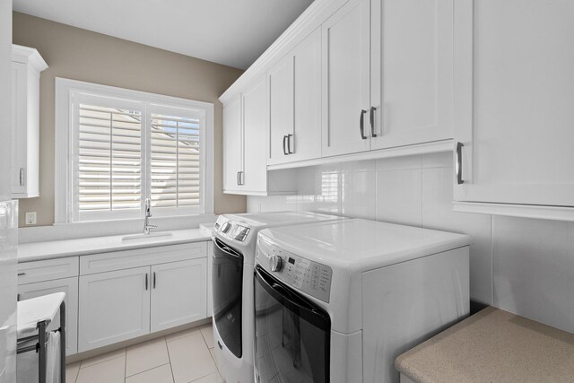 washroom featuring a sink, cabinet space, light tile patterned flooring, and washer and clothes dryer