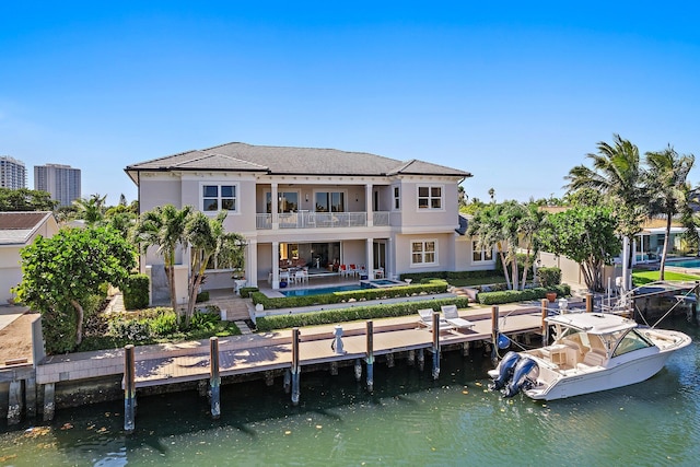 back of property with stucco siding, a water view, a balcony, and a patio area