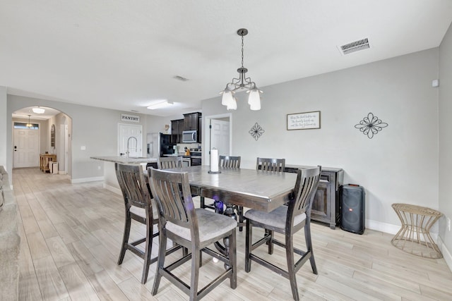 3558 SW Pisano St, Port Saint Lucie, FL 34953 - dining area featuring an inviting chandelier, arched walkways, visible vents, and light wood-type flooring