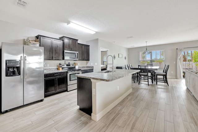 3558 SW Pisano St, Port Saint Lucie, FL 34953 - kitchen with visible vents, an island with sink, a sink, appliances with stainless steel finishes, and light wood-type flooring