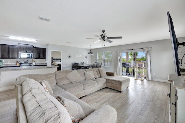 3558 SW Pisano St, Port Saint Lucie, FL 34953 - living room with baseboards, a ceiling fan, visible vents, and light wood-type flooring