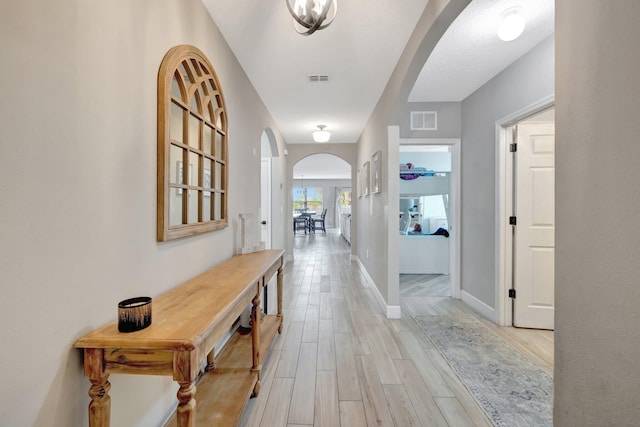 3558 SW Pisano St, Port Saint Lucie, FL 34953 - hall featuring arched walkways, visible vents, baseboards, and light wood-style floors