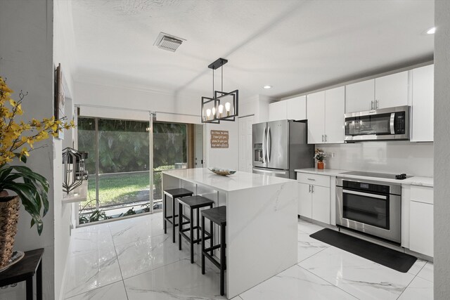 kitchen with a kitchen bar, visible vents, marble finish floor, white cabinetry, and stainless steel appliances