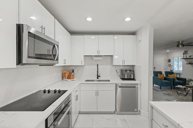 kitchen with light countertops, appliances with stainless steel finishes, white cabinets, a ceiling fan, and a sink