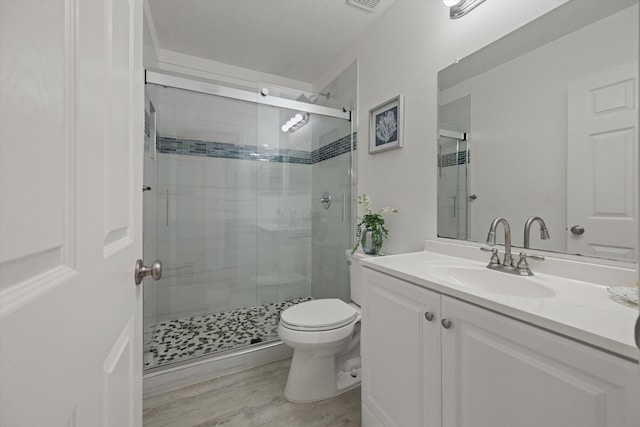 bathroom featuring visible vents, toilet, a stall shower, wood finished floors, and vanity