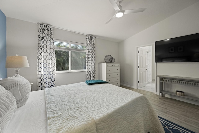 bedroom with a ceiling fan, lofted ceiling, wood finished floors, and connected bathroom